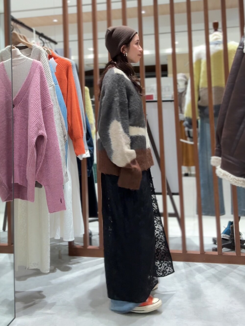 グレー系のニット/セーター、ブラック系のワンピース、ブルー系のデニムパンツを着用したレディースの秋コーディネートの7枚目の写真