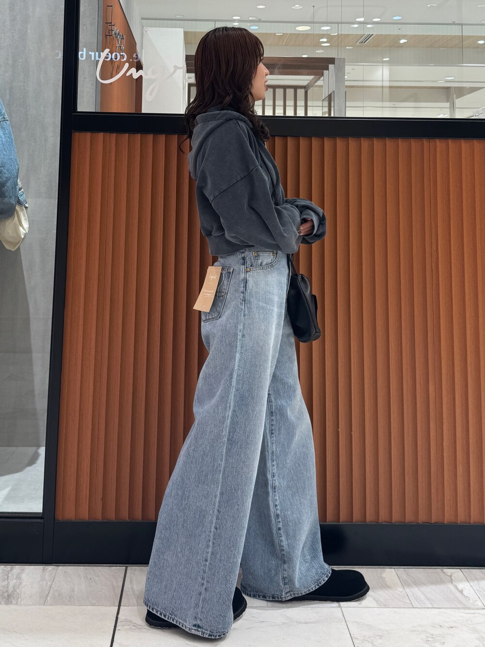 ブルー系のデニムパンツ、グレー系のパーカー、ブラック系のスリッポンを着用したレディースの秋コーディネートの4枚目の写真