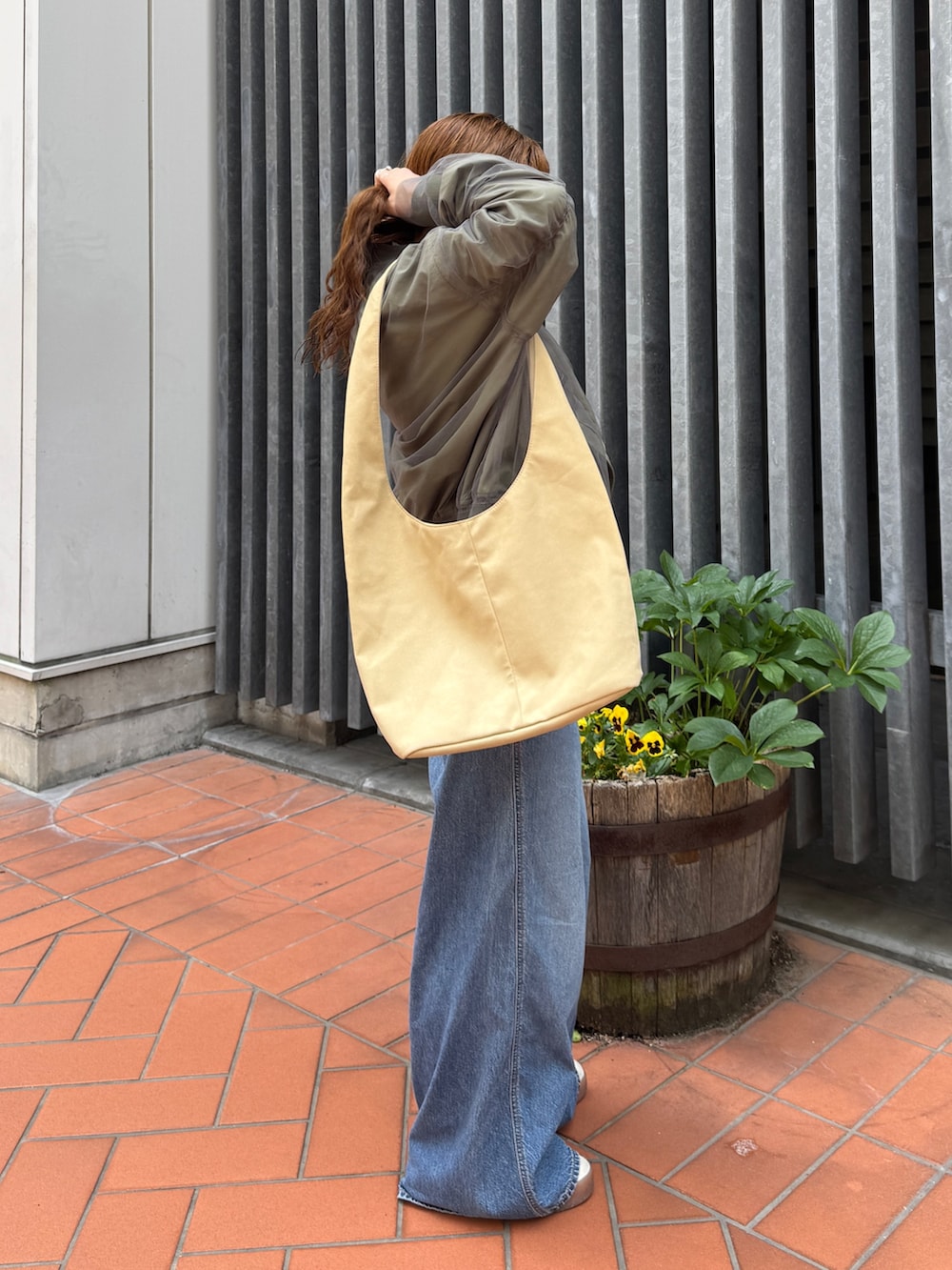 ベージュ系のトートバッグ、ホワイト系のタンクトップ、ブルー系のデニムパンツを着用したレディースの夏コーディネートの5枚目の写真