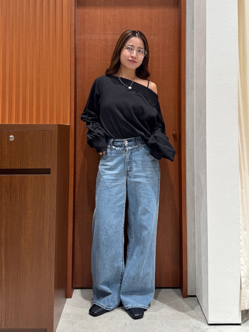 ブルー系のデニムパンツ、ブラック系のスウェット、シルバー系のメガネを着用したレディースの秋コーディネートの6枚目の写真