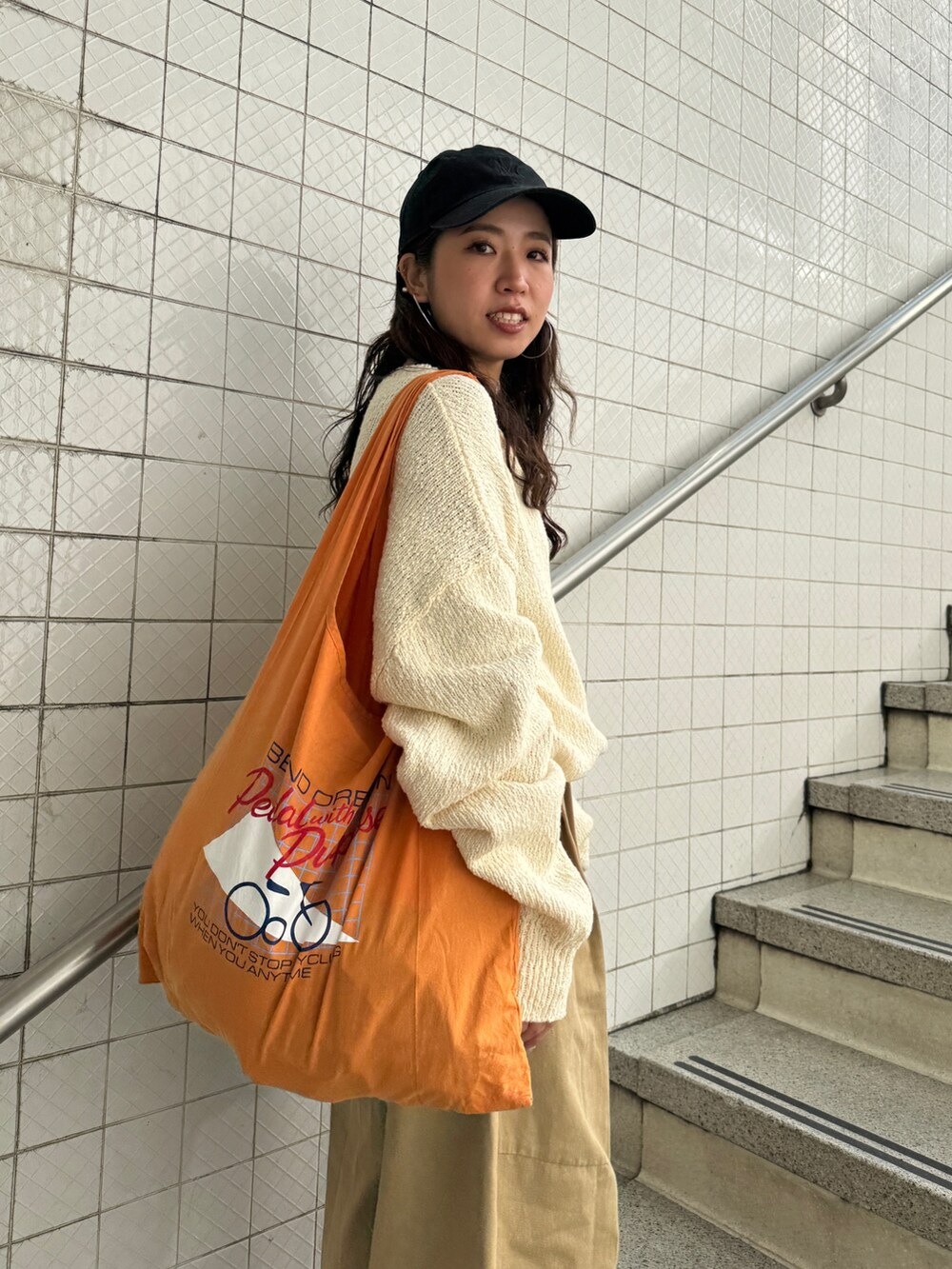 ベージュ系のチノパンツ、ホワイト系のニット/セーター、オレンジ系のエコバッグ/サブバッグを着用したレディースの冬コーディネートの7枚目の写真