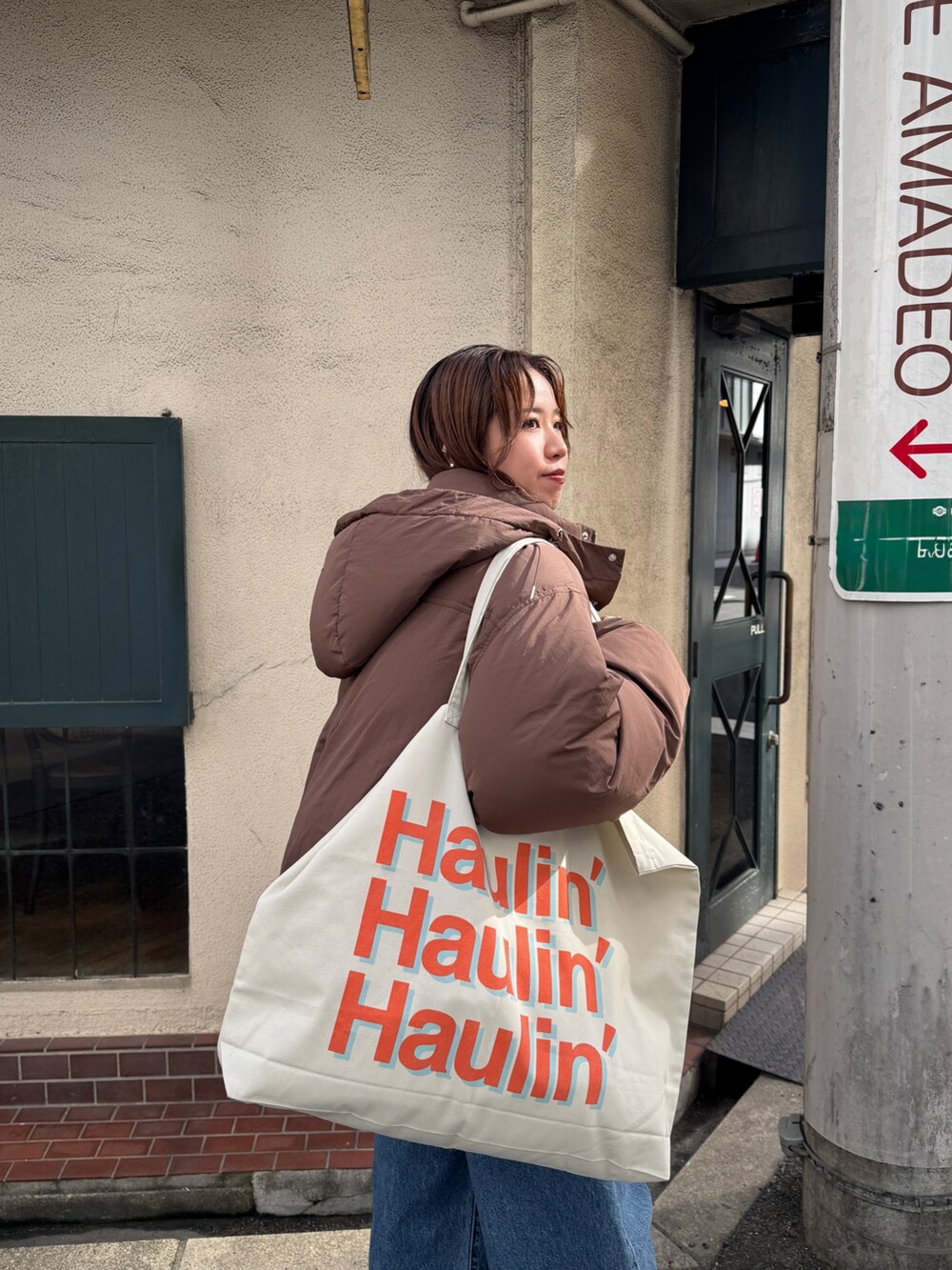 ブラウン系のダウンジャケット/コート、ホワイト系のニット/セーター、ブルー系のデニムパンツを着用したレディースの秋コーディネートの4枚目の写真