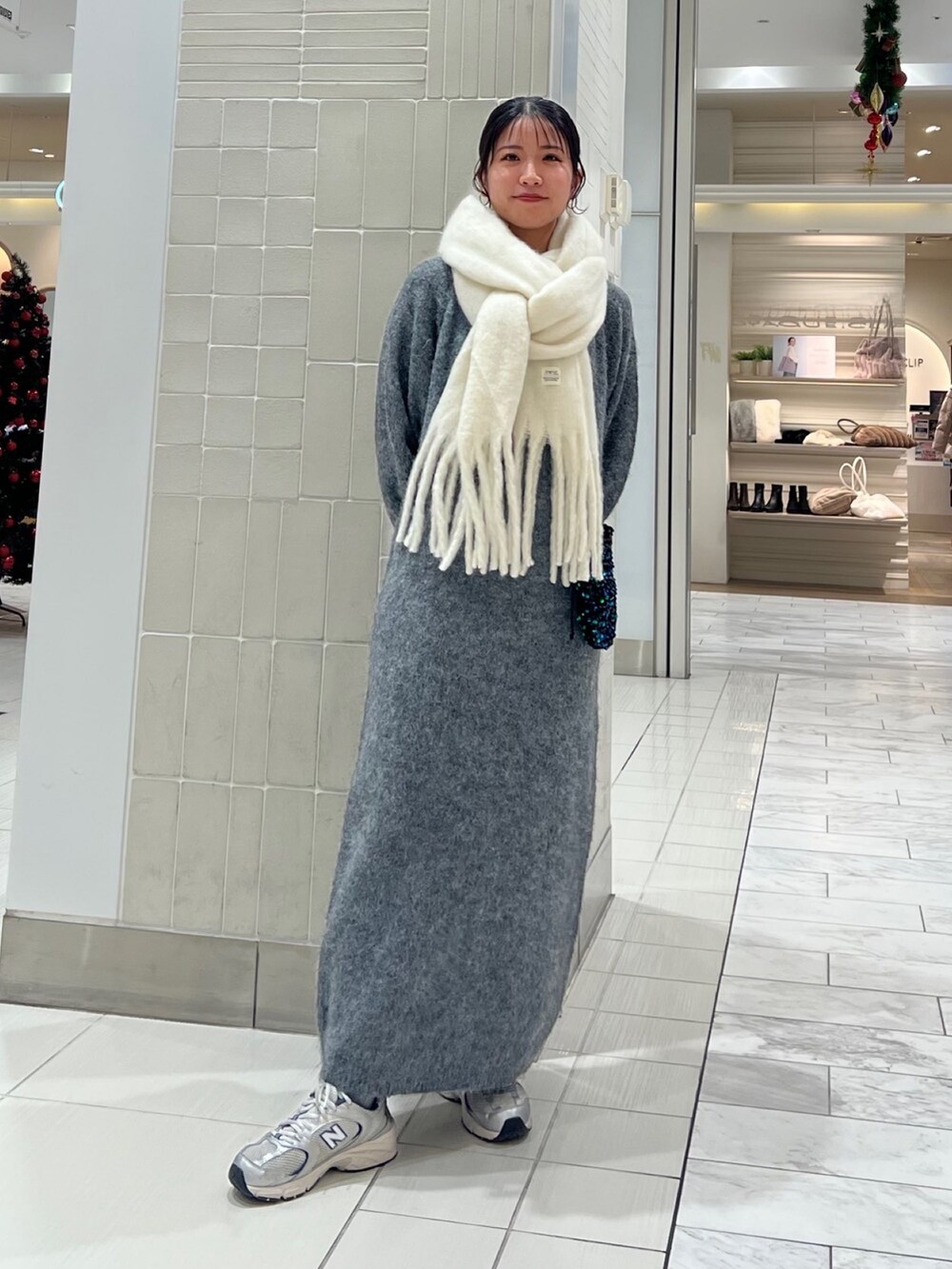 グレー系のワンピース、グリーン系のショルダーバッグ、ホワイト系のマフラーを着用したレディースの秋コーディネートの10枚目の写真