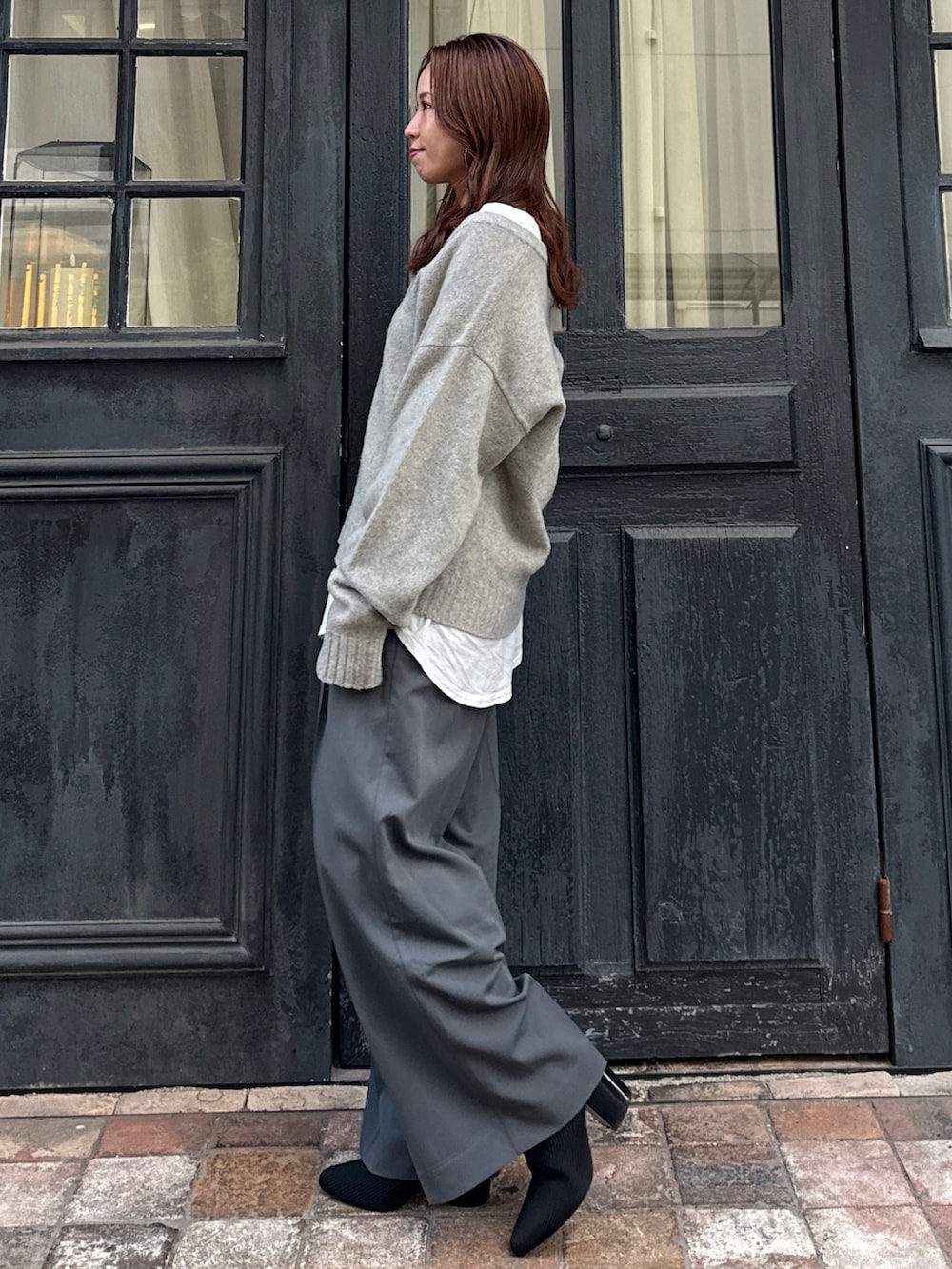 グレー系のニット/セーター、ホワイト系のTシャツ/カットソー、グレー系のその他パンツを着用したレディースの冬コーディネートの5枚目の写真