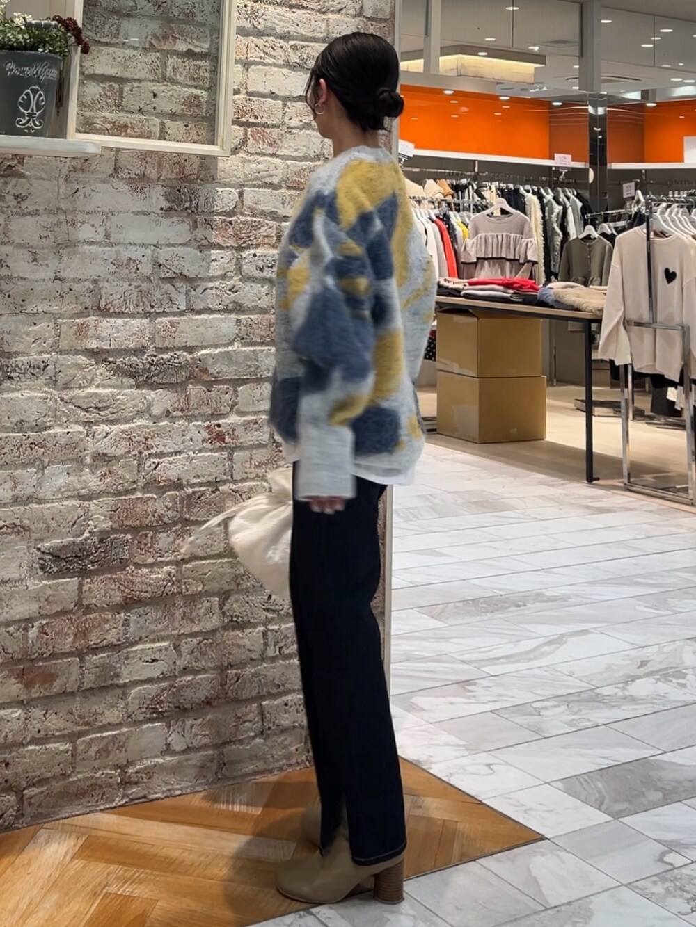 ブルー系のニット/セーター、ホワイト系のハンドバッグ、ブルー系のデニムパンツを着用したレディースの秋コーディネートの6枚目の写真