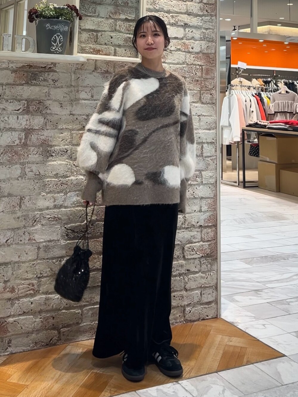 ブラック系のスカート、ブラック系のハンドバッグ、ベージュ系のニット/セーターを着用したレディースの秋コーディネートの6枚目の写真