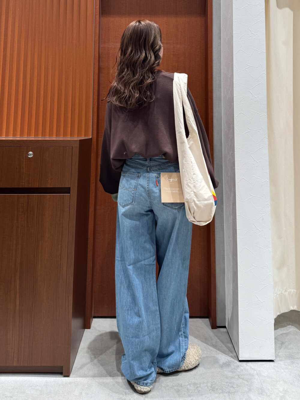 ブルー系のデニムパンツ、ブラウン系のニット/セーター、ホワイト系のトートバッグを着用したレディースの冬コーディネートの5枚目の写真