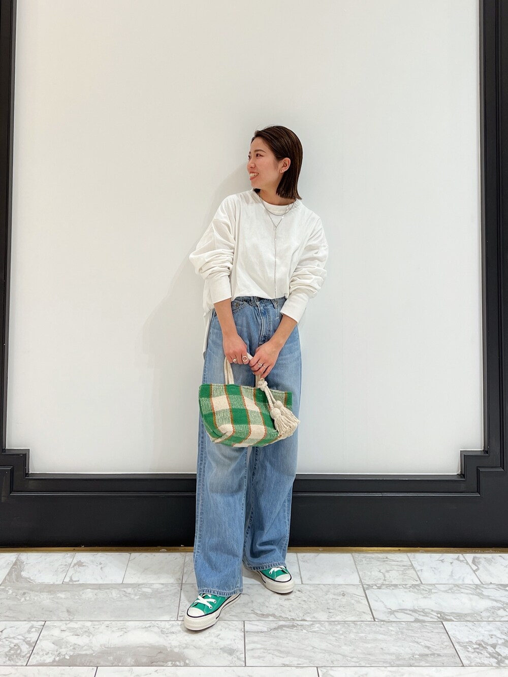 ブルー系のデニムパンツ、グリーン系のスニーカーを着用したレディースの春コーディネートの4枚目の写真