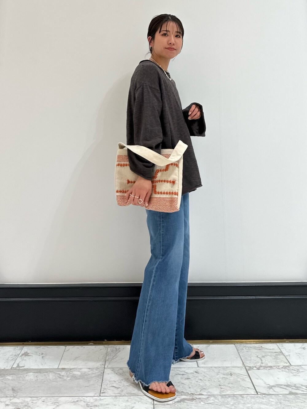 グレー系のニット/セーター、ブルー系のデニムパンツ、ブラック系のサンダルを着用したレディースの春コーディネートの4枚目の写真