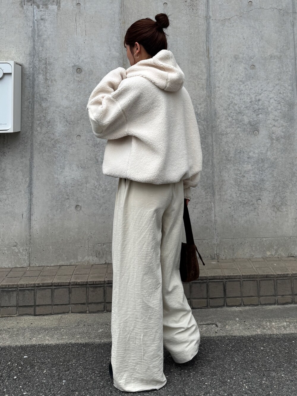 ホワイト系のパーカー、ホワイト系のその他パンツ、ブラウン系のハンドバッグを着用したレディースの秋コーディネートの6枚目の写真