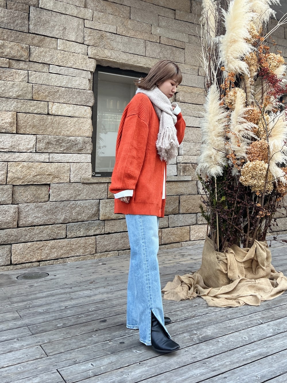 オレンジ系のカーディガン/ボレロ、ブルー系のデニムパンツを着用したレディースの秋コーディネートの3枚目の写真