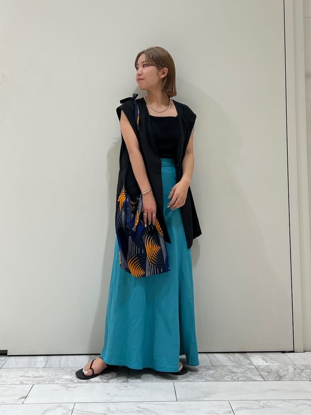 ブラック系のベスト、ブラック系のサンダル、ブルー系のスカートを着用したレディースの夏コーディネートの5枚目の写真