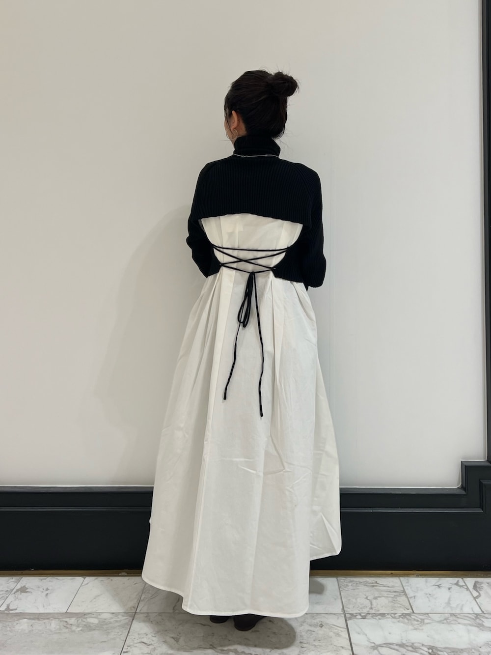 ブラック系のワンピース、グリーン系のハンドバッグ、ブラウン系のブーツを着用したレディースの冬コーディネートの3枚目の写真