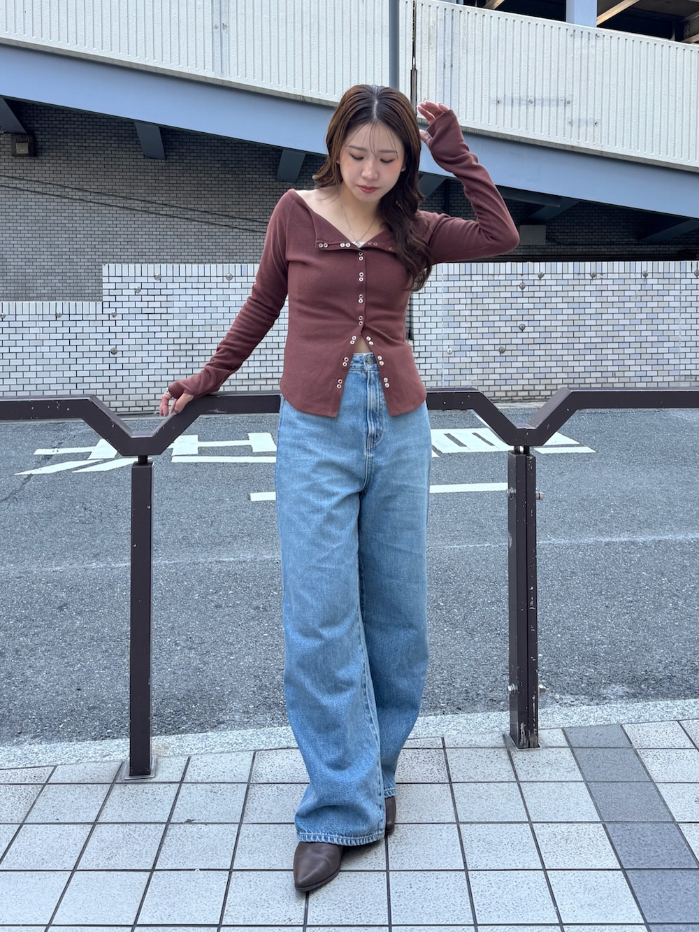 ブルー系のデニムパンツ、ブラウン系のTシャツ/カットソー、ブラウン系のブーツを着用したレディースの秋コーディネートの4枚目の写真