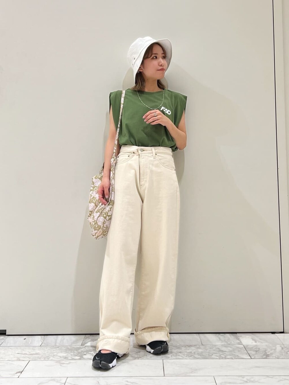 ホワイト系のデニムパンツ、グリーン系のタンクトップ、ホワイト系のハットを着用したレディースの春コーディネートの3枚目の写真