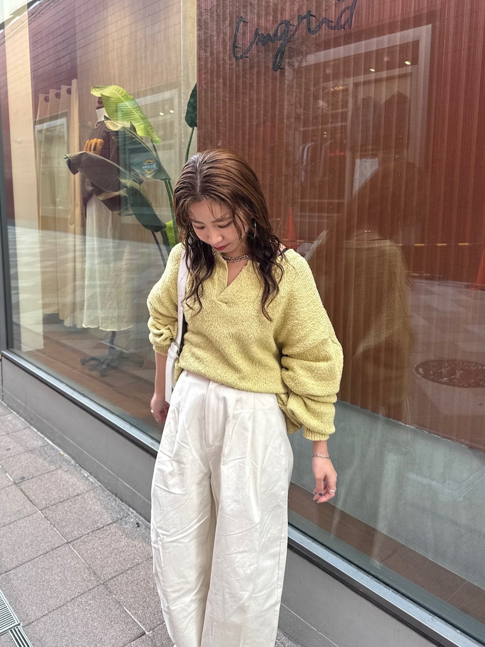 ホワイト系のチノパンツ、グリーン系のニット/セーター、ホワイト系のショルダーバッグを着用したレディースの冬コーディネートの7枚目の写真