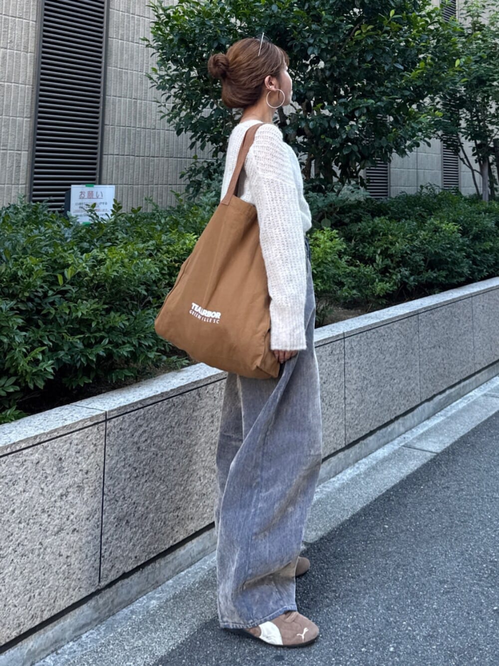 ベージュ系のデニムパンツ、ホワイト系のニット/セーター、ブラウン系のトートバッグを着用したレディースの夏コーディネートの3枚目の写真