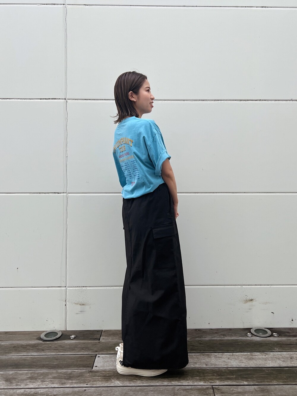 ブルー系のTシャツ/カットソー、ブラック系のスカート、ホワイト系のスニーカーを着用したレディースの春コーディネートの6枚目の写真