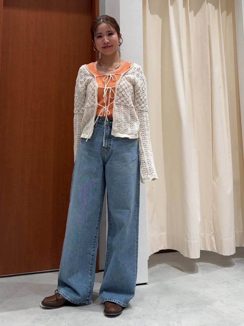 ブルー系のデニムパンツ、オレンジ系のタンクトップ、ホワイト系のカーディガン/ボレロを着用したレディースの春コーディネートの7枚目の写真