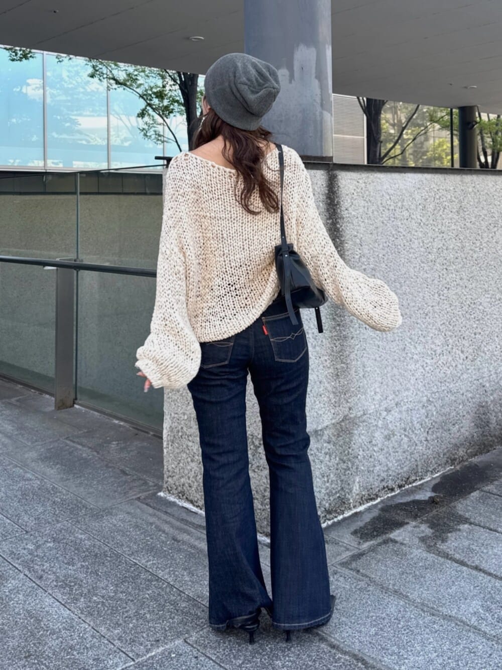 ブラック系のハンドバッグ、ブルー系のデニムパンツ、ブラック系のパンプスを着用したレディースの秋コーディネートの3枚目の写真