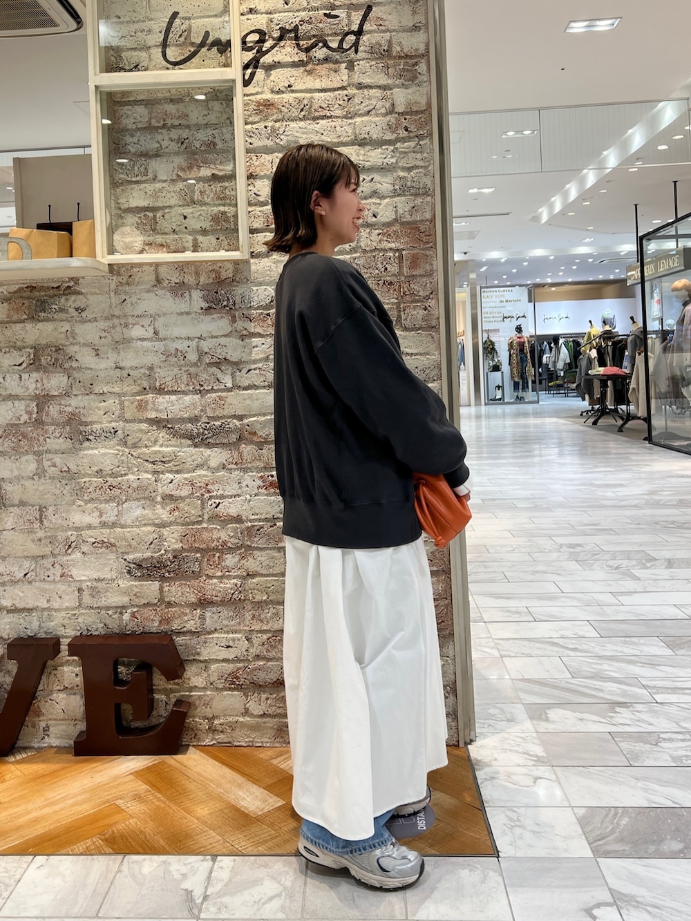 グレー系のスウェット、ブラック系のワンピース、ブルー系のデニムパンツを着用したレディースの冬コーディネートの3枚目の写真