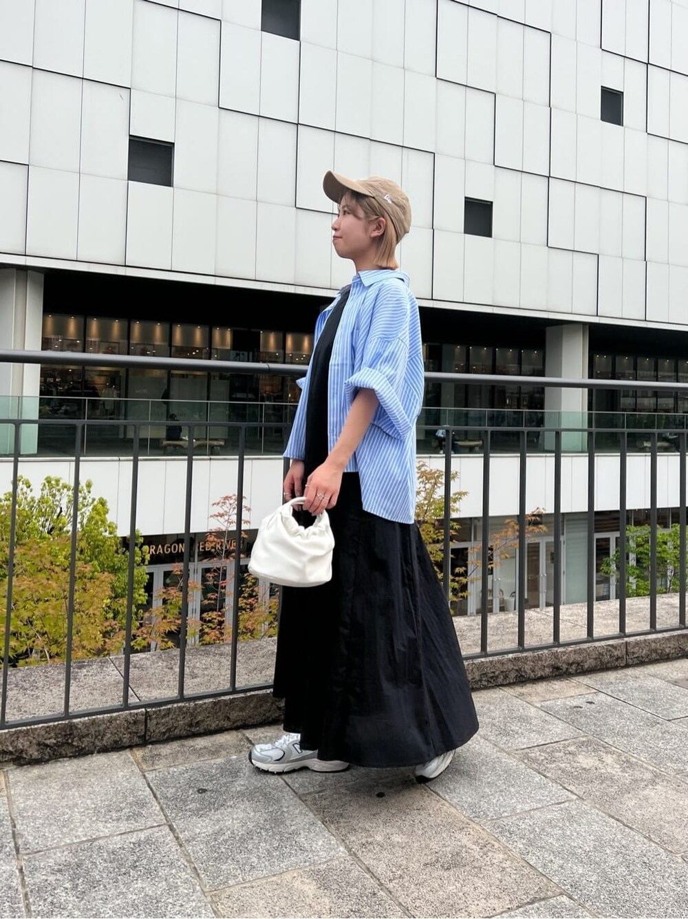 ブラック系のワンピース、ブルー系のシャツ/ブラウス、ホワイト系のハンドバッグを着用したレディースの春コーディネートの4枚目の写真