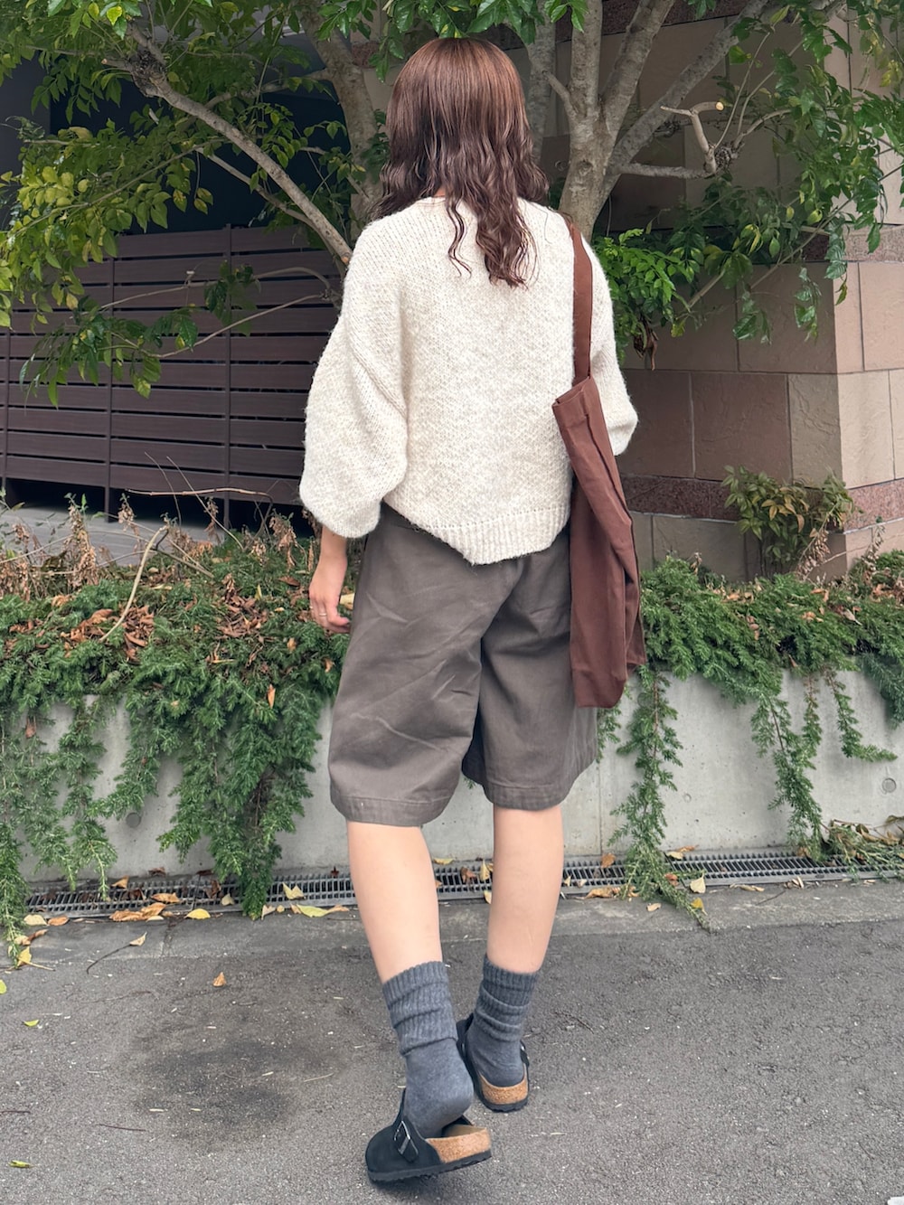 グレー系のチノパンツ、ホワイト系のニット/セーター、ブラウン系のトートバッグを着用したレディースの秋コーディネートの6枚目の写真