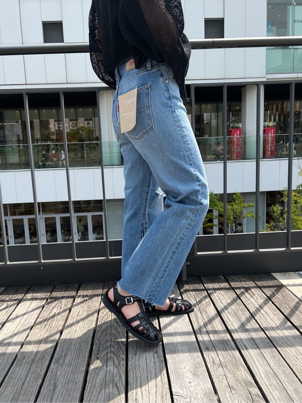 ブラック系のサンダル、ブルー系のデニムパンツ、ブラック系のTシャツ/カットソーを着用したレディースの春コーディネートの7枚目の写真