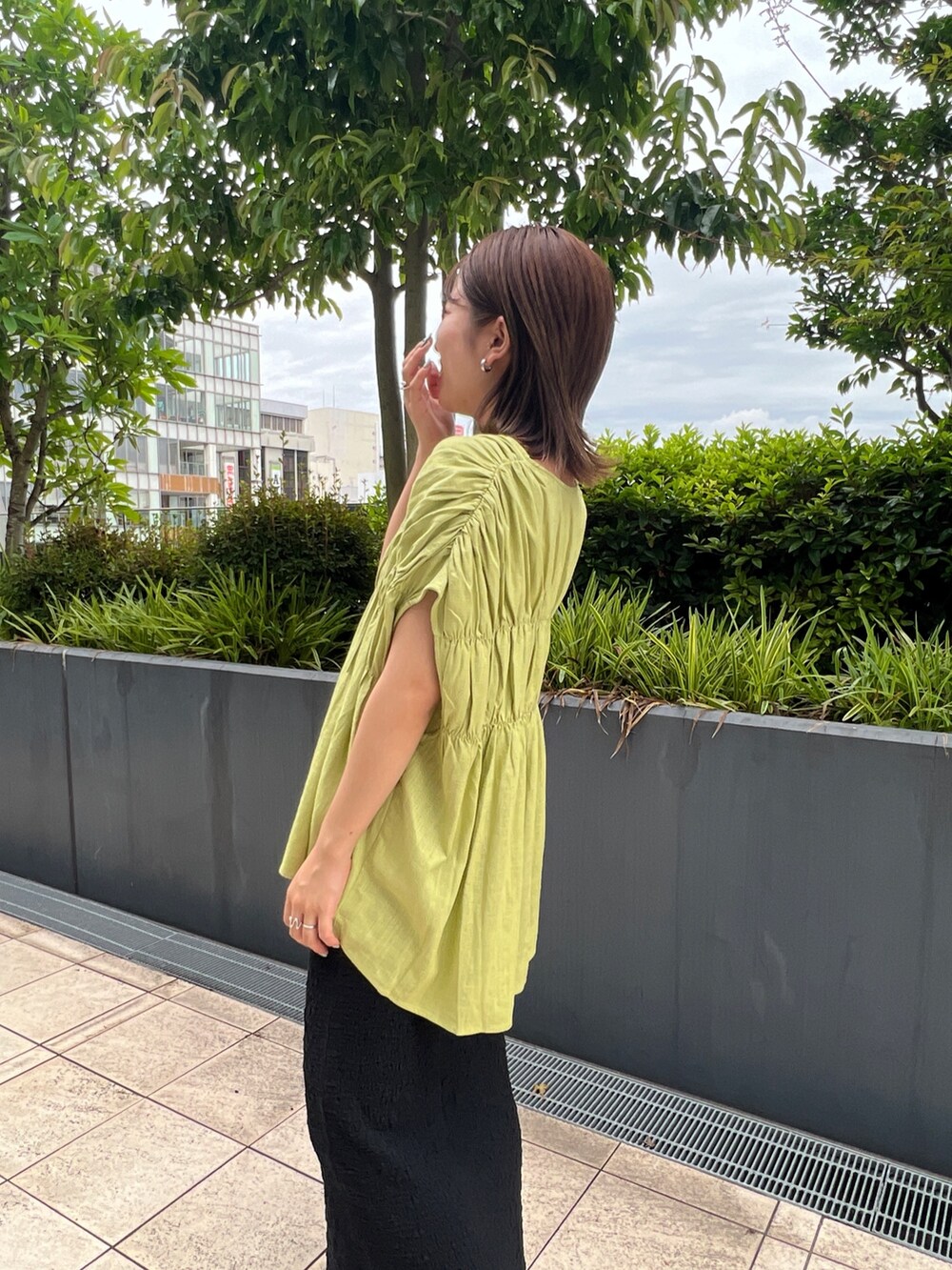 グリーン系のシャツ/ブラウス、ブラック系のスカート、ブラック系のサンダルを着用したレディースの夏コーディネートの5枚目の写真