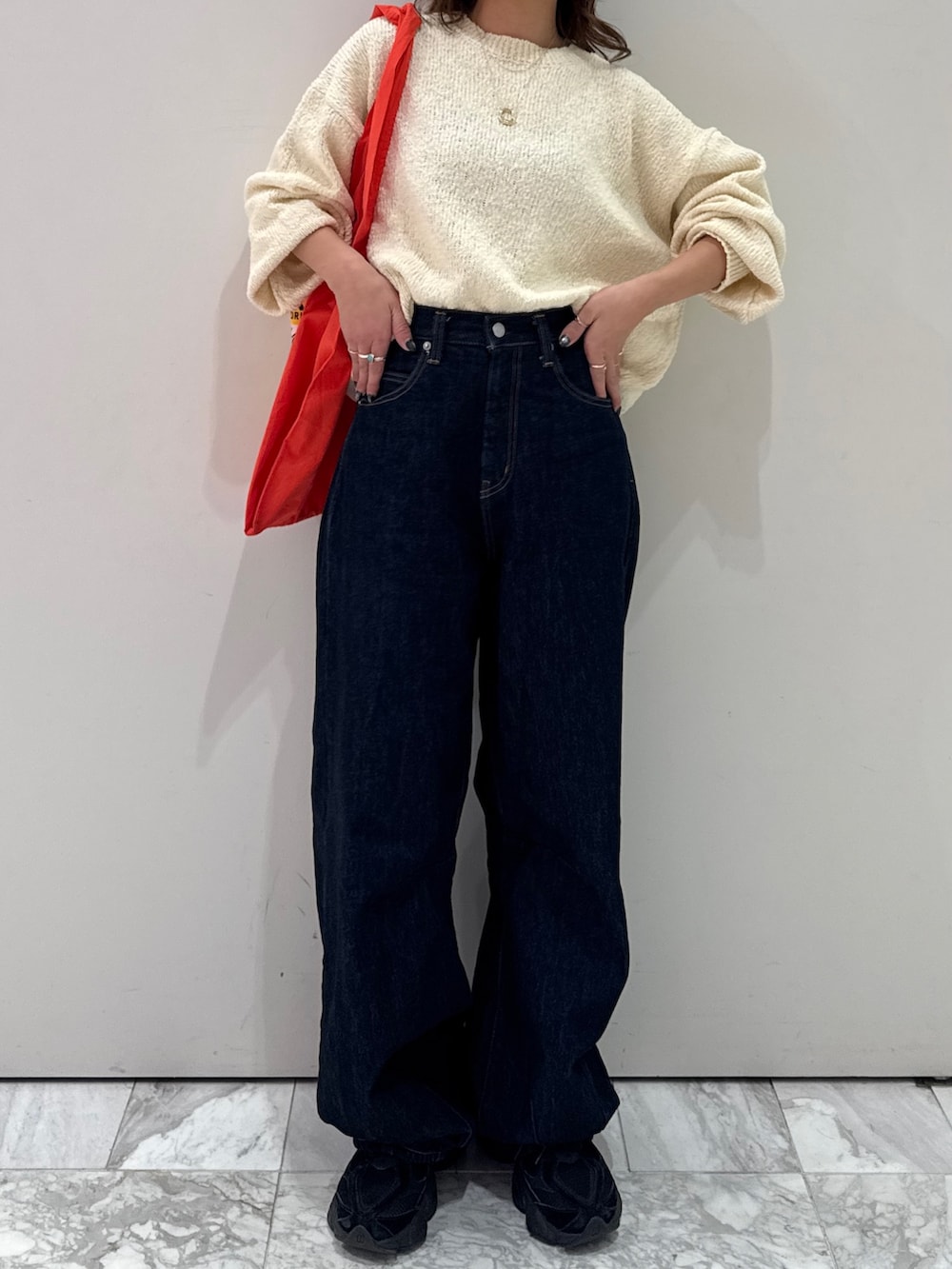 ブルー系のデニムパンツ、ホワイト系のニット/セーター、オレンジ系のトートバッグを着用したレディースの冬コーディネートの7枚目の写真