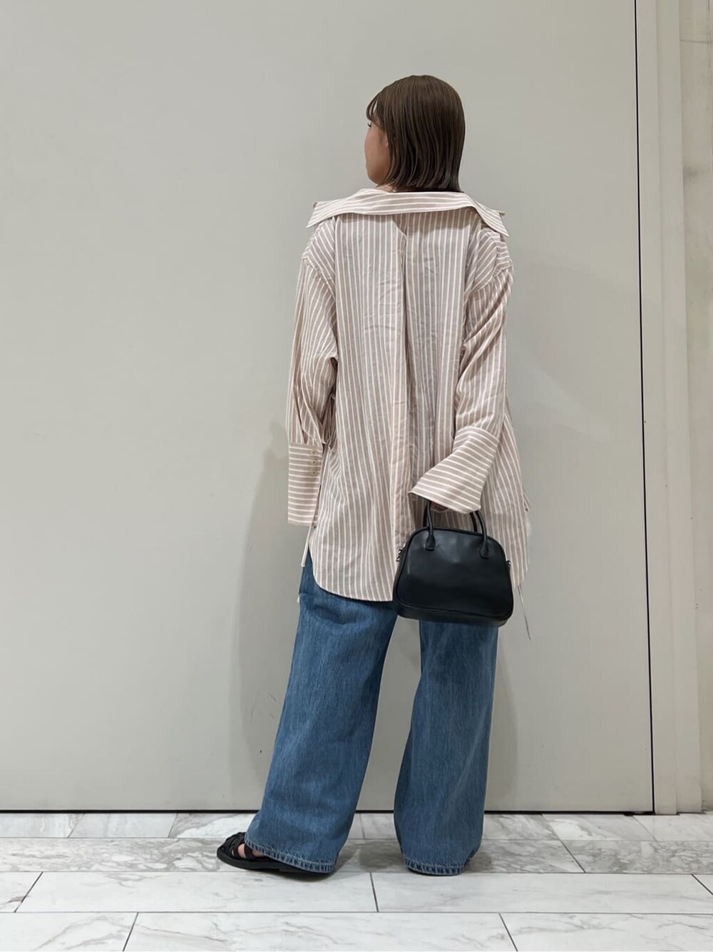 ブラック系のサンダル、ピンク系のシャツ/ブラウス、ブラック系のハンドバッグを着用したレディースの春コーディネートの5枚目の写真