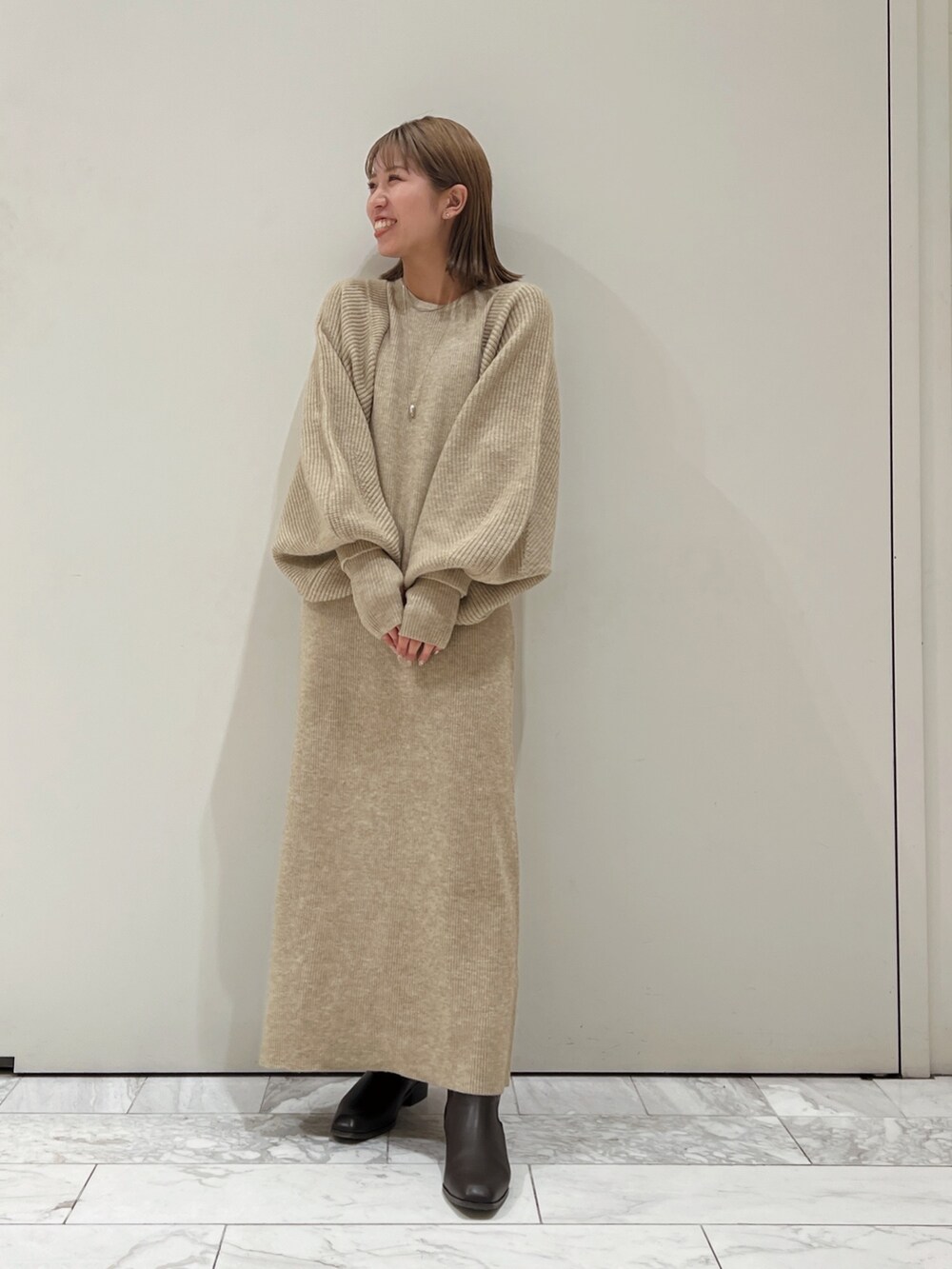グレー系のワンピース、ブラウン系のブーツを着用したレディースの秋コーディネートの2枚目の写真