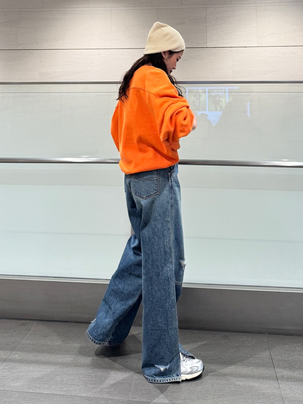 ブルー系のデニムパンツ、オレンジ系のスウェットを着用したレディースの冬コーディネートの3枚目の写真