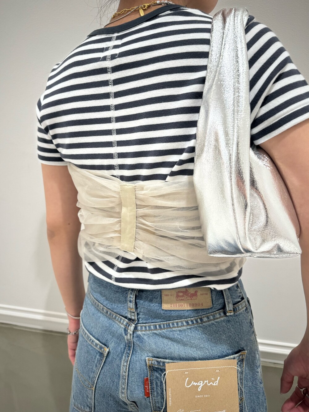 グレー系のTシャツ/カットソー、ベージュ系のキャミソール、ブルー系のデニムパンツを着用したレディースの春コーディネートの10枚目の写真