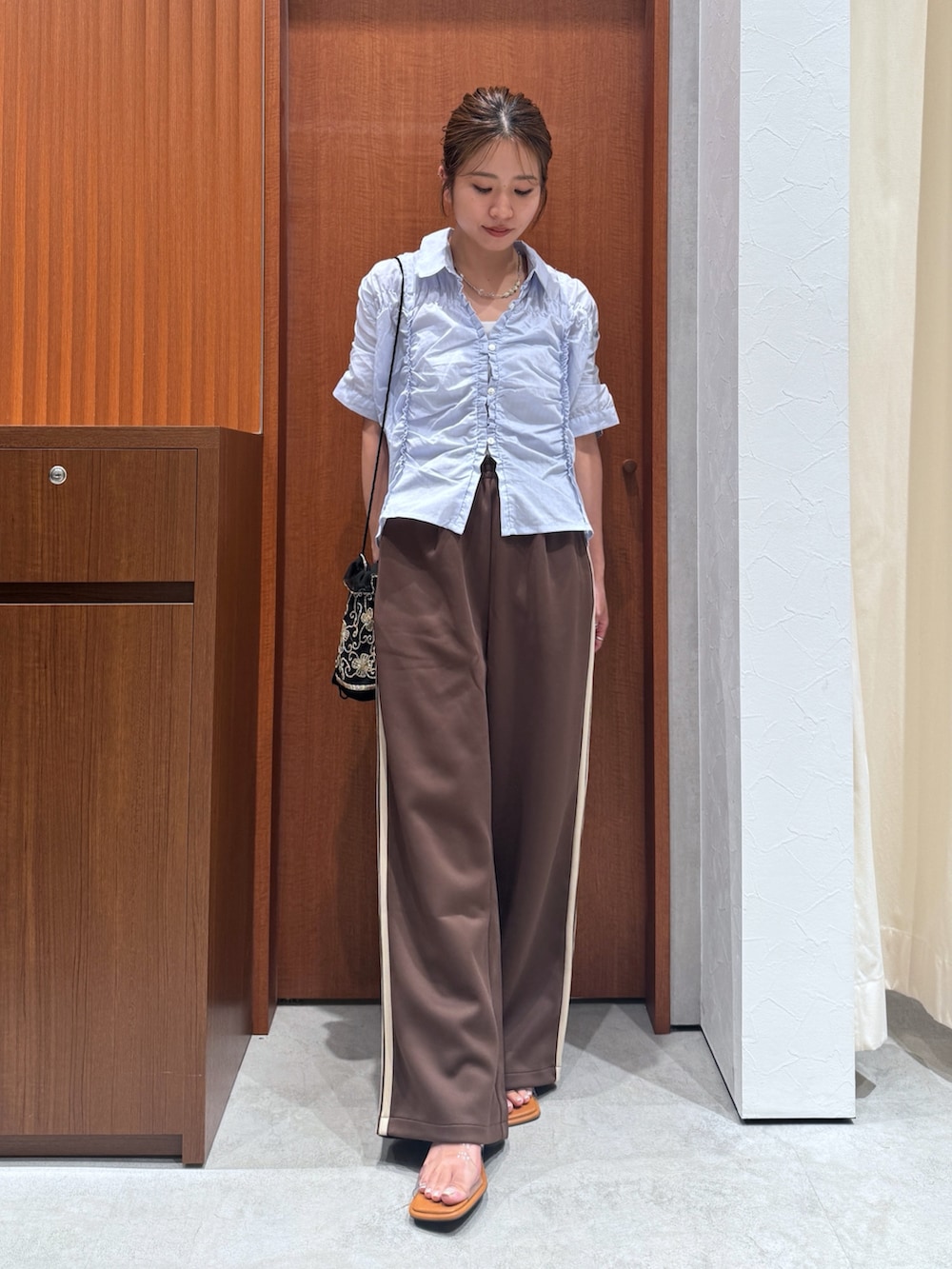 ブラウン系のその他パンツ、ブルー系のシャツ/ブラウス、ブラック系のハンドバッグを着用したレディースの夏コーディネートの6枚目の写真