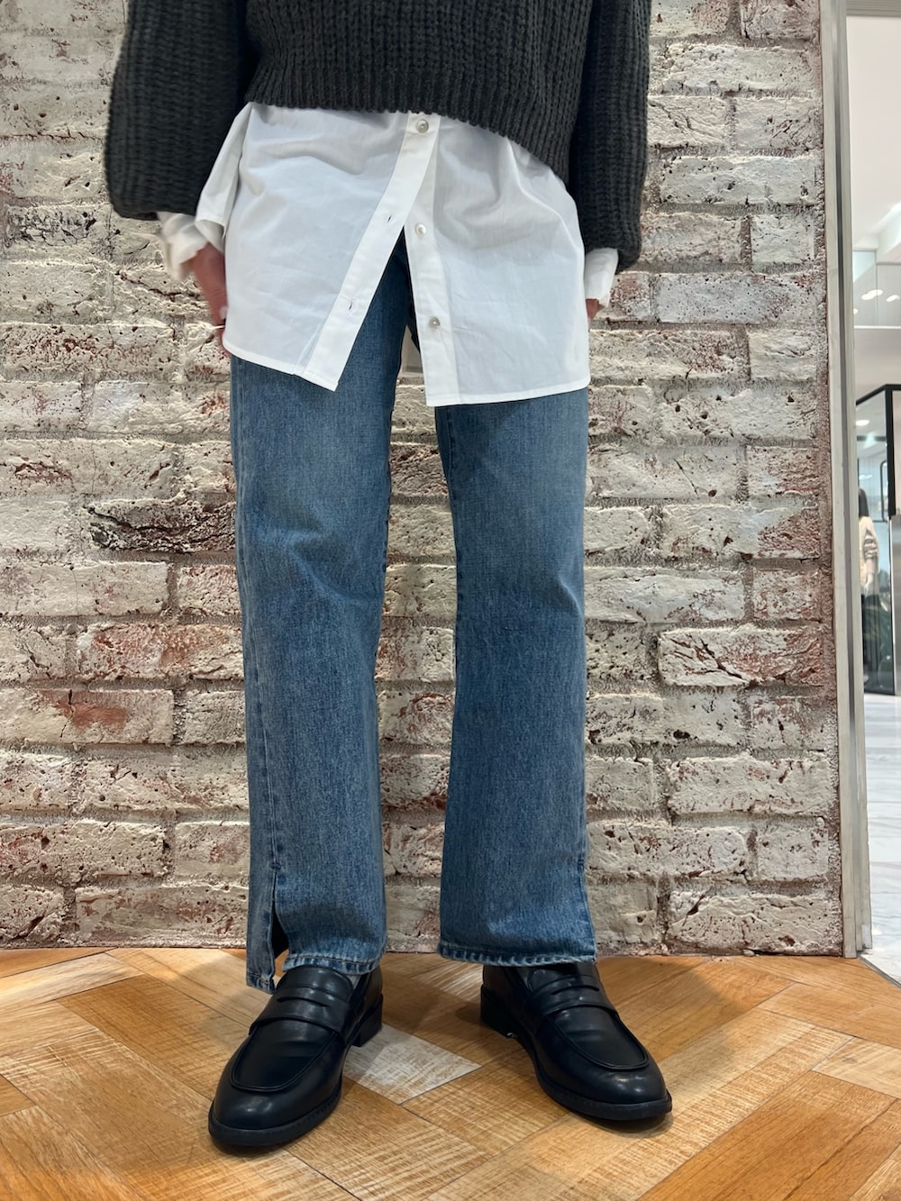 グレー系のニット/セーター、ブルー系のデニムパンツ、ブラック系のローファーを着用したレディースの秋コーディネートの7枚目の写真