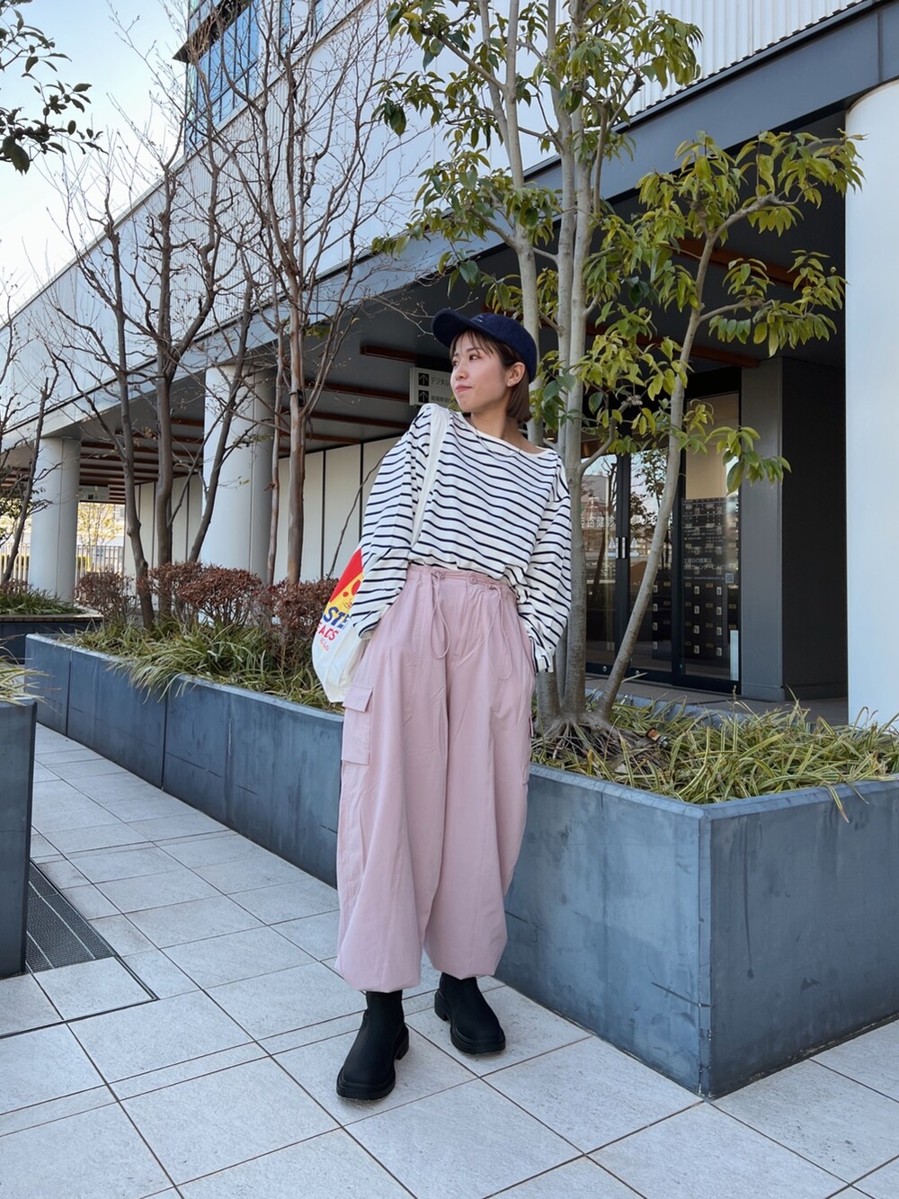 ピンク系のカーゴパンツ、ホワイト系のエコバッグ/サブバッグ、ブルー系のTシャツ/カットソーを着用したレディースの冬コーディネートの2枚目の写真