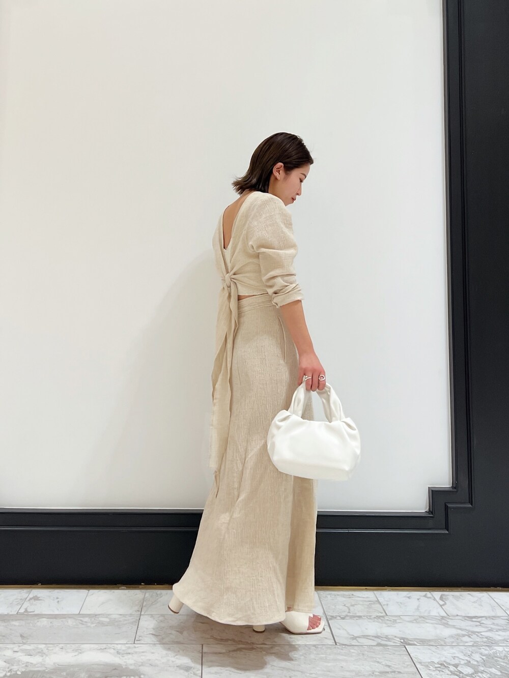 ホワイト系のベスト、ホワイト系のワンピース、ホワイト系のハンドバッグを着用したレディースの春コーディネートの5枚目の写真