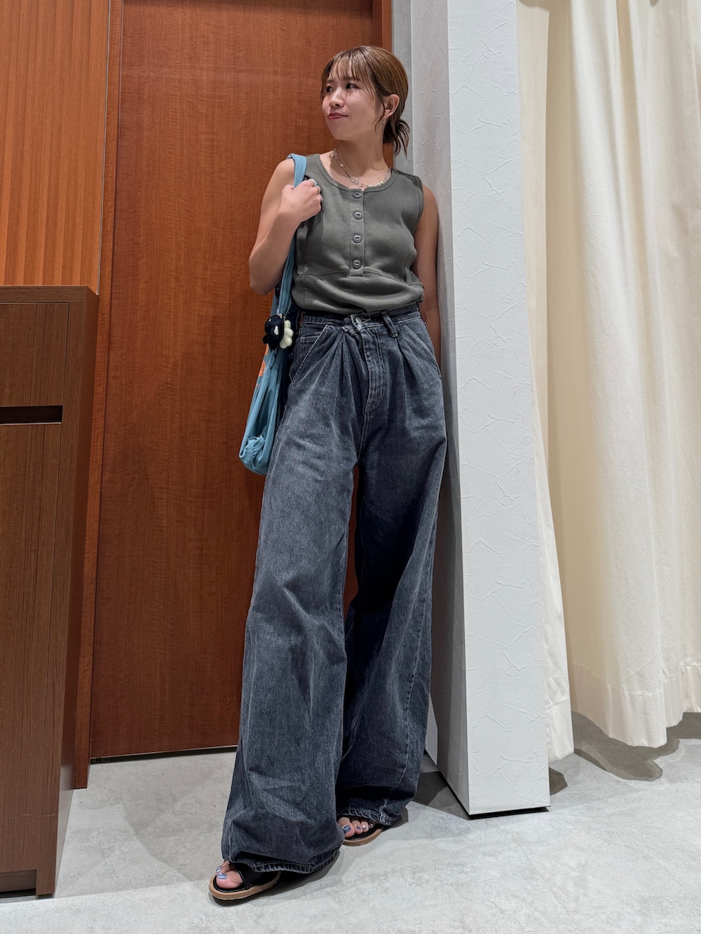 ブラック系のデニムパンツ、グレー系のタンクトップ、ブルー系のトートバッグを着用したレディースの夏コーディネートの6枚目の写真