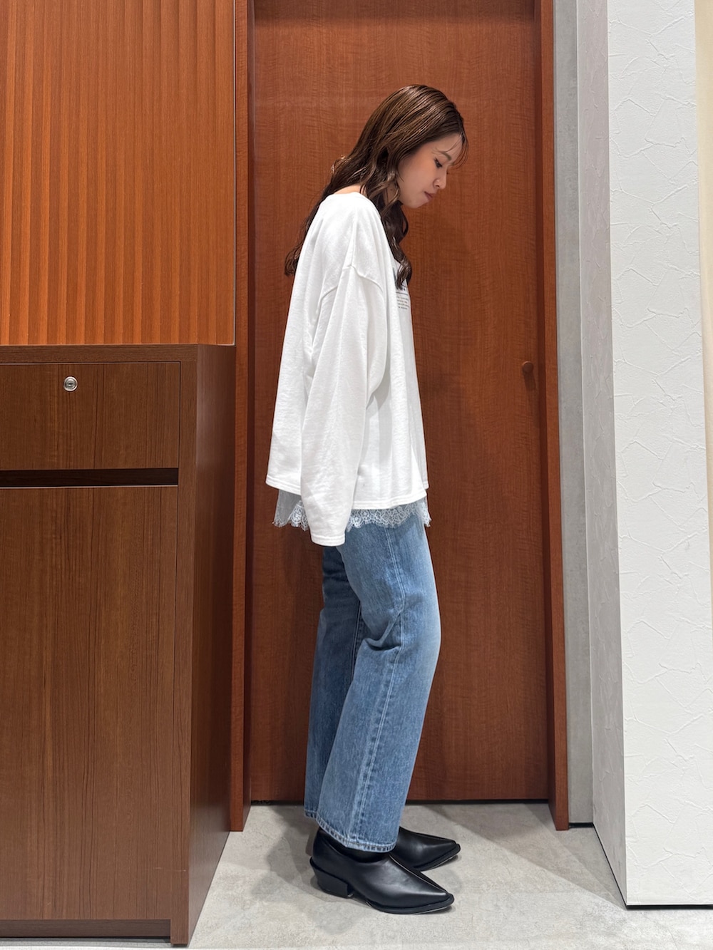 グレー系のキャミソール、ホワイト系のスウェット、ブルー系のデニムパンツを着用したレディースの秋コーディネートの2枚目の写真