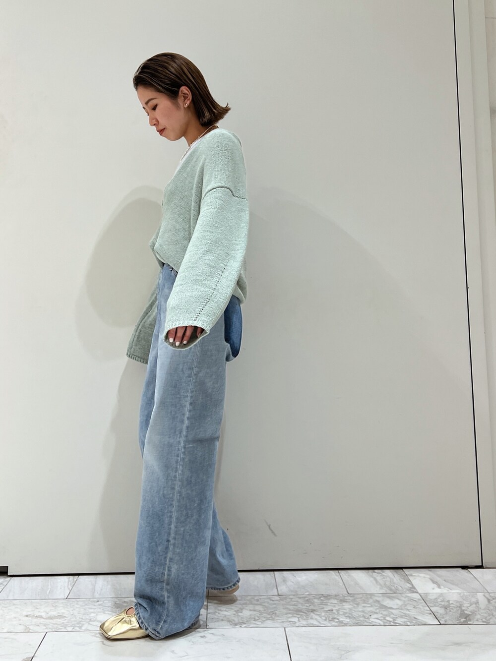 ブルー系のデニムパンツ、イエロー系のパンプス、グリーン系のニット/セーターを着用したレディースの冬コーディネートの4枚目の写真