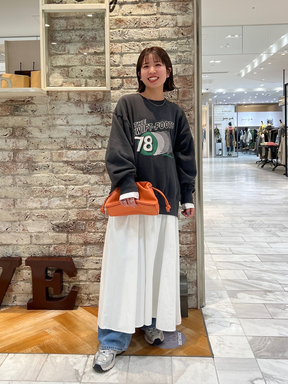 グレー系のスウェット、ブラック系のワンピース、ブルー系のデニムパンツを着用したレディースの冬コーディネートの2枚目の写真