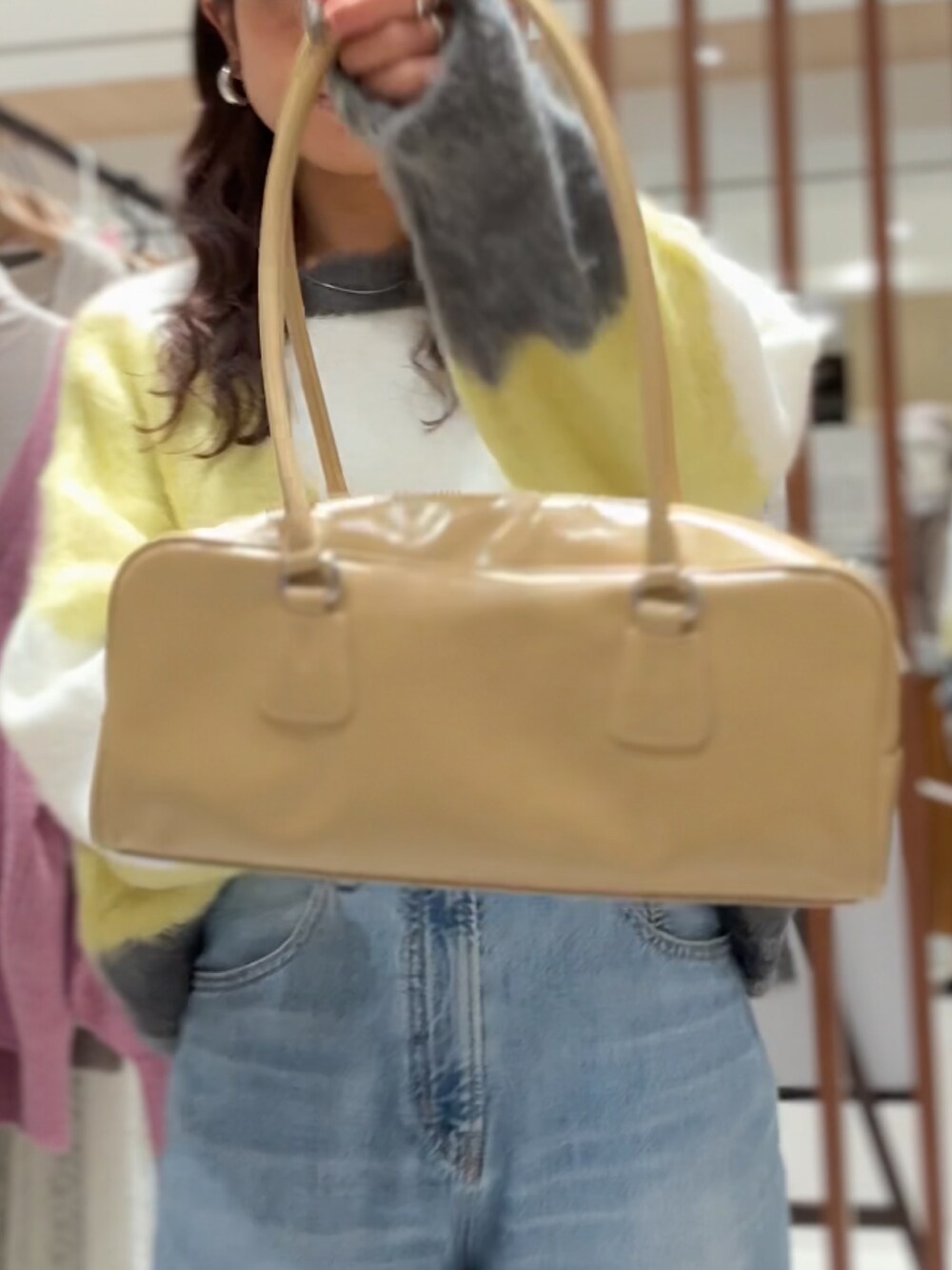 グリーン系のニット/セーター、ブルー系のデニムパンツ、ベージュ系のハンドバッグを着用したレディースの秋コーディネートの4枚目の写真