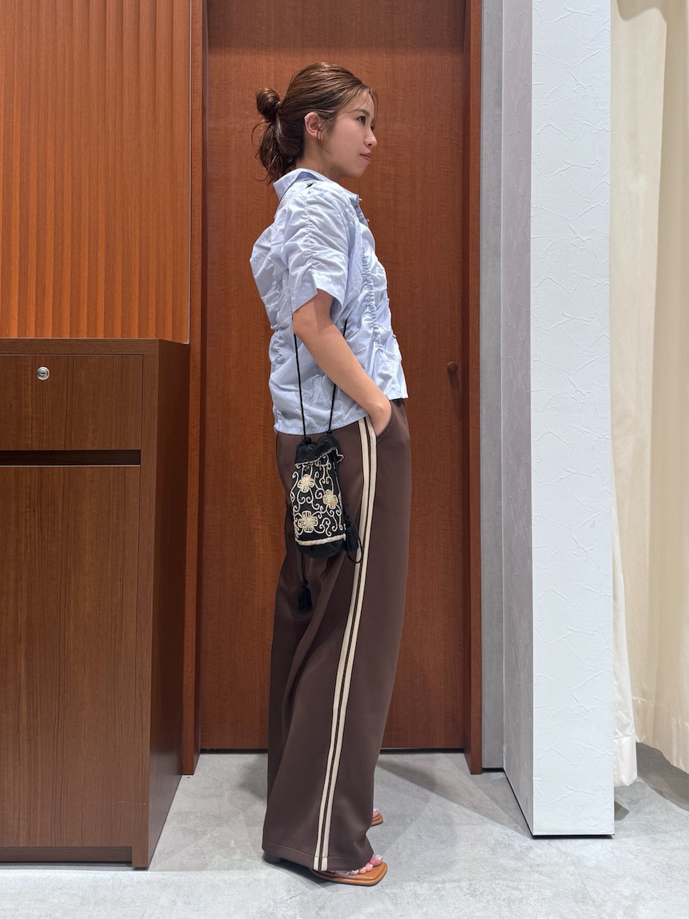 ブラウン系のその他パンツ、ブルー系のシャツ/ブラウス、ブラック系のハンドバッグを着用したレディースの夏コーディネートの2枚目の写真