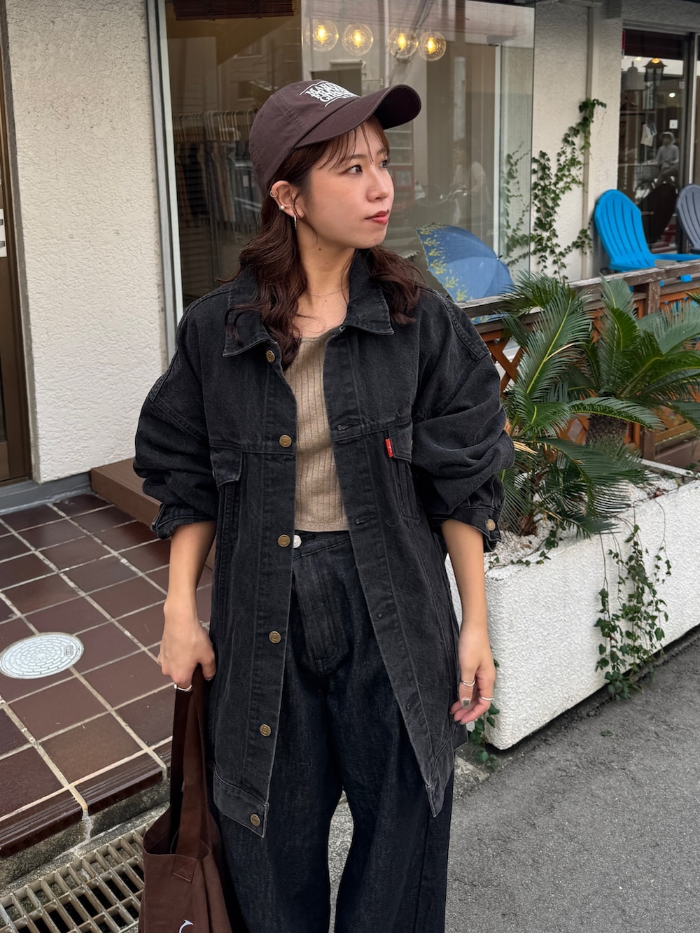 ブラック系のデニムジャケット、ブラック系のデニムパンツ、ブラウン系のトートバッグを着用したレディースの秋コーディネートの6枚目の写真