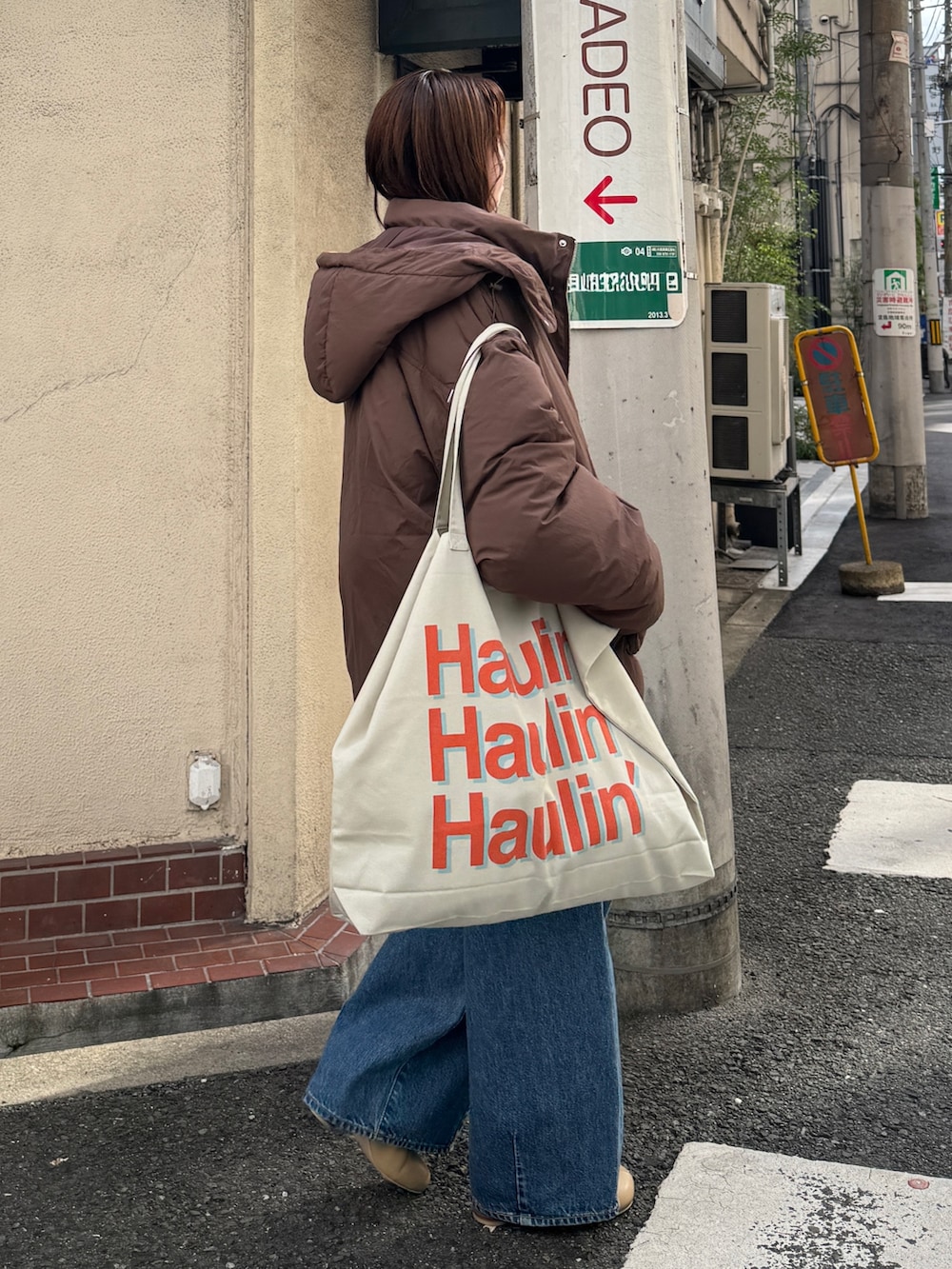 ブラウン系のダウンジャケット/コート、ホワイト系のニット/セーター、ブルー系のデニムパンツを着用したレディースの秋コーディネートの2枚目の写真