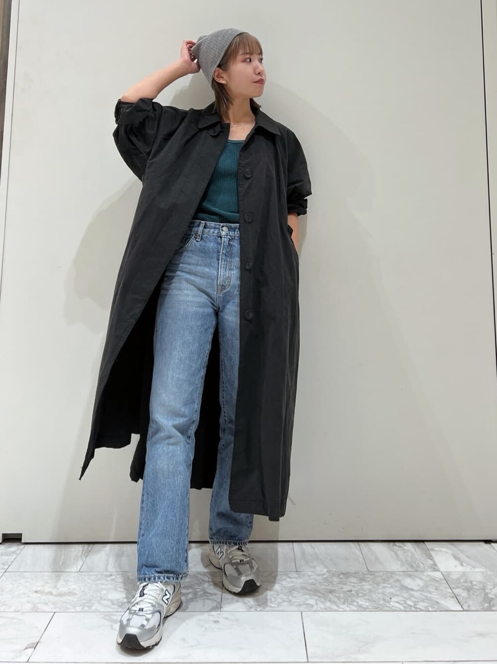 ブラック系のステンカラーコート、グリーン系のTシャツ/カットソー、ブルー系のデニムパンツを着用したレディースの秋コーディネートの2枚目の写真