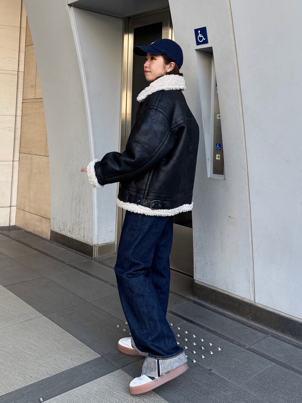 ブルー系のデニムパンツ、ホワイト系のカーディガン/ボレロ、ブラック系のブルゾンを着用したレディースの冬コーディネートの5枚目の写真