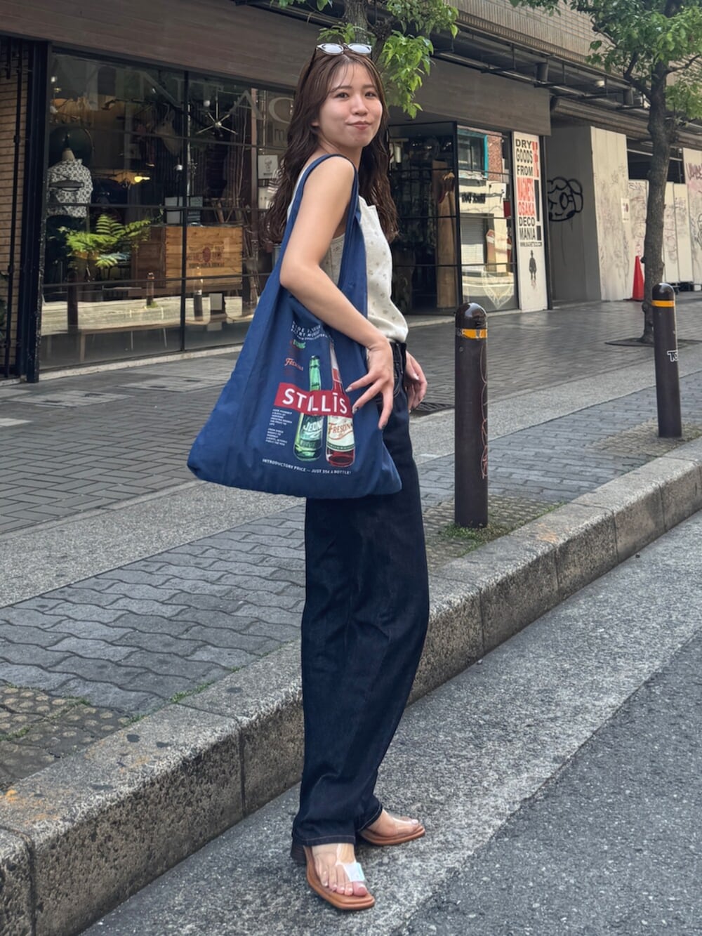 ブルー系のデニムパンツ、その他のサンダル、ブルー系のトートバッグを着用したレディースの春コーディネートの4枚目の写真