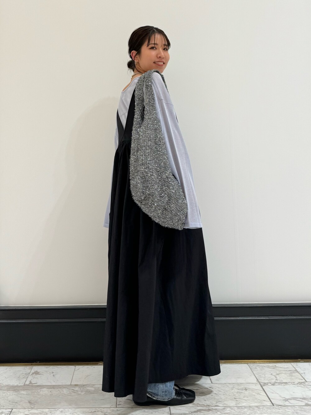 ブラック系のワンピース、ブルー系のニット/セーター、ブルー系のデニムパンツを着用したレディースの春コーディネートの6枚目の写真